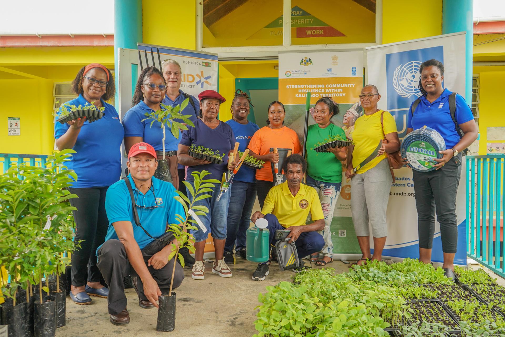 Smiling group of people posing outside a yellow building with blue columns.
