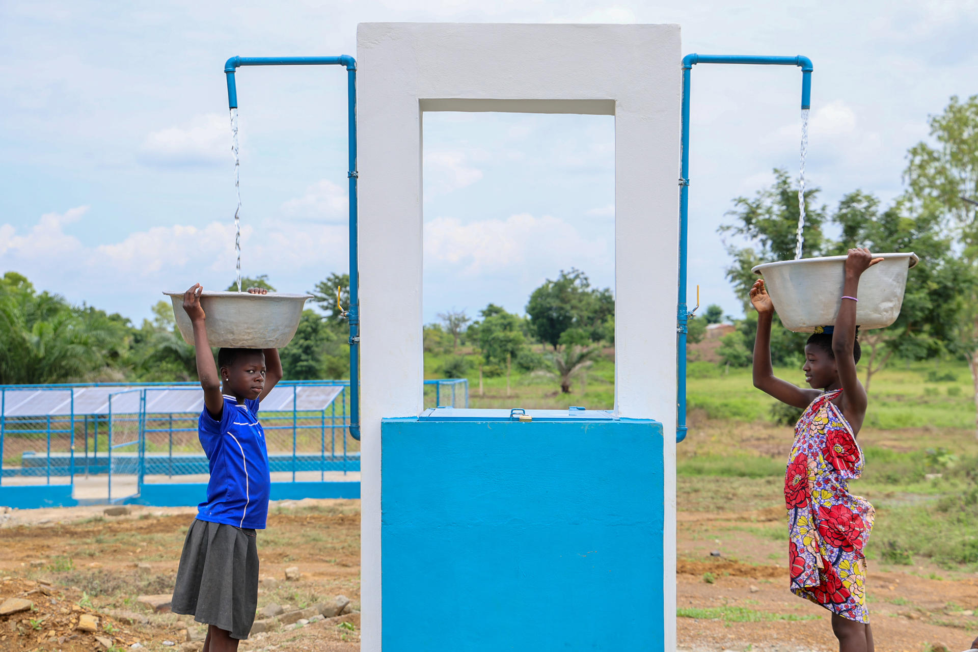 Des filles prenant de l'eau à une borne fontaine