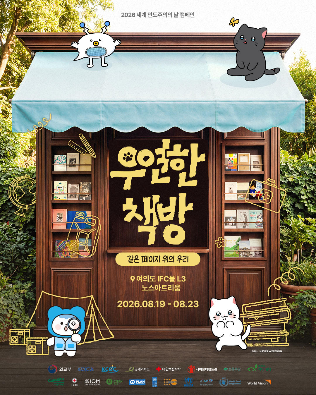 Wooden storefront with blue awning, Korean sign, and cute animal characters; autumn trees in back.