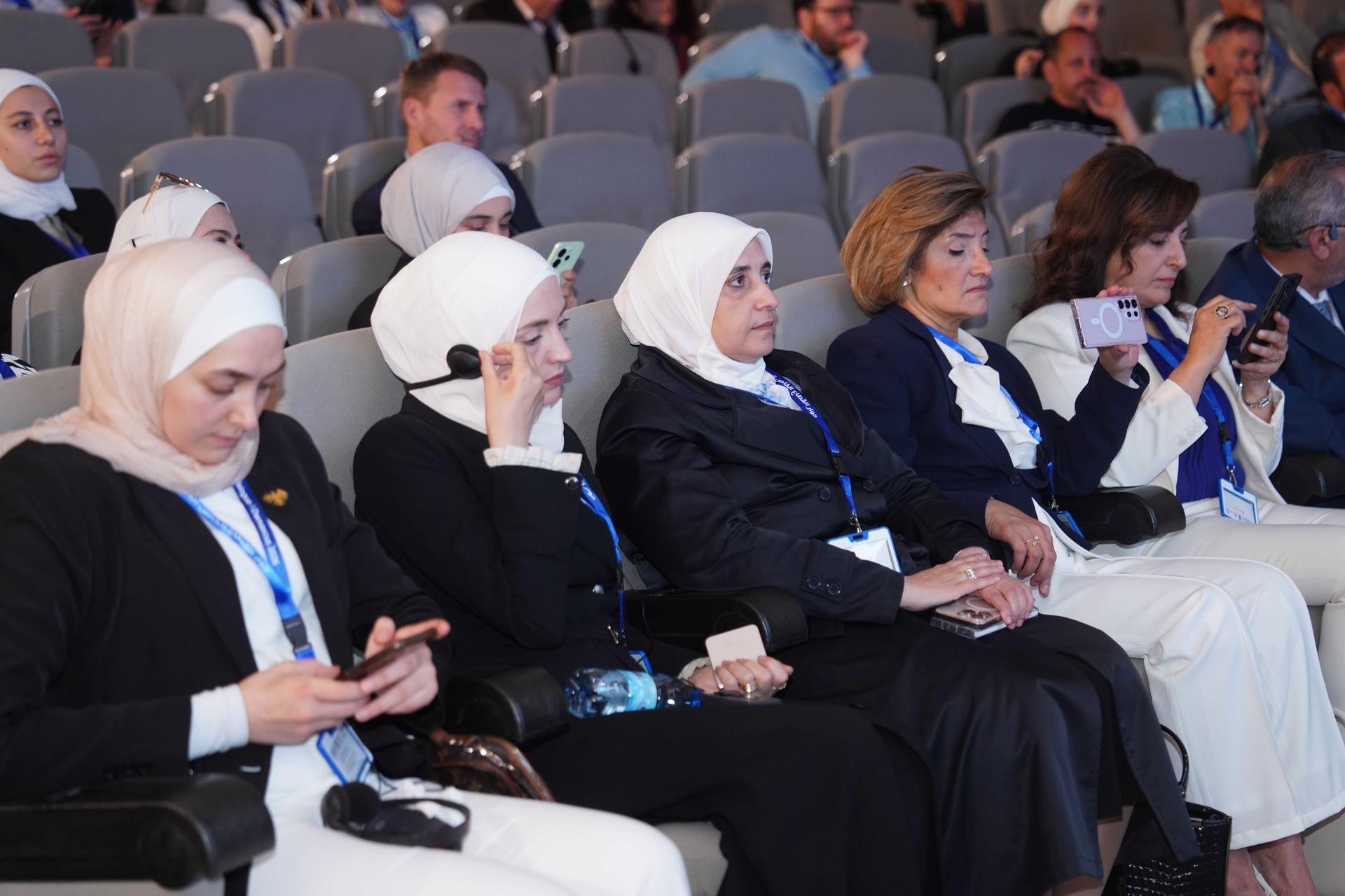Audience seated in an auditorium during a conference; several women wearing headscarves.