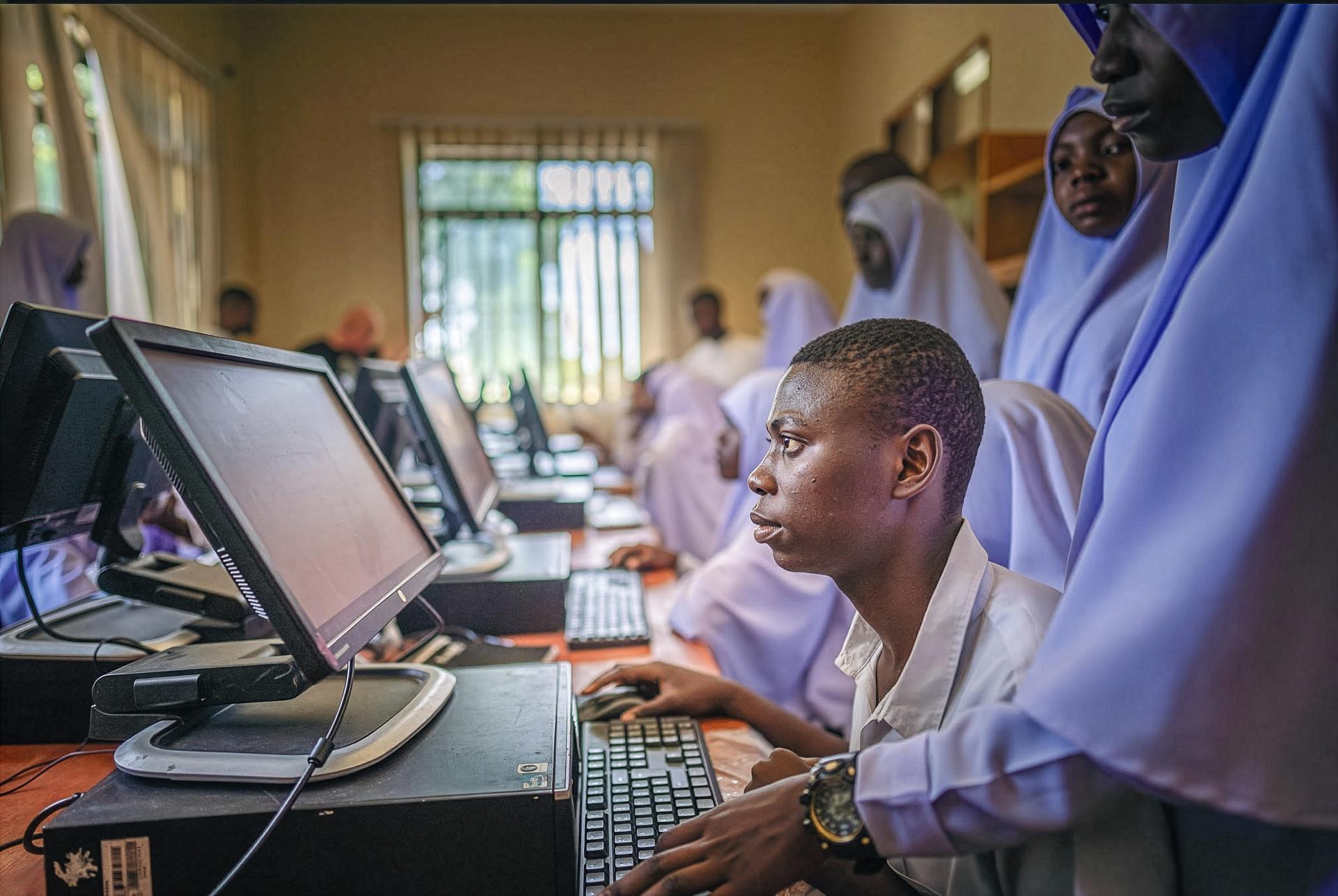 Student in lavender uniform using a desktop computer in a classroom computer lab.