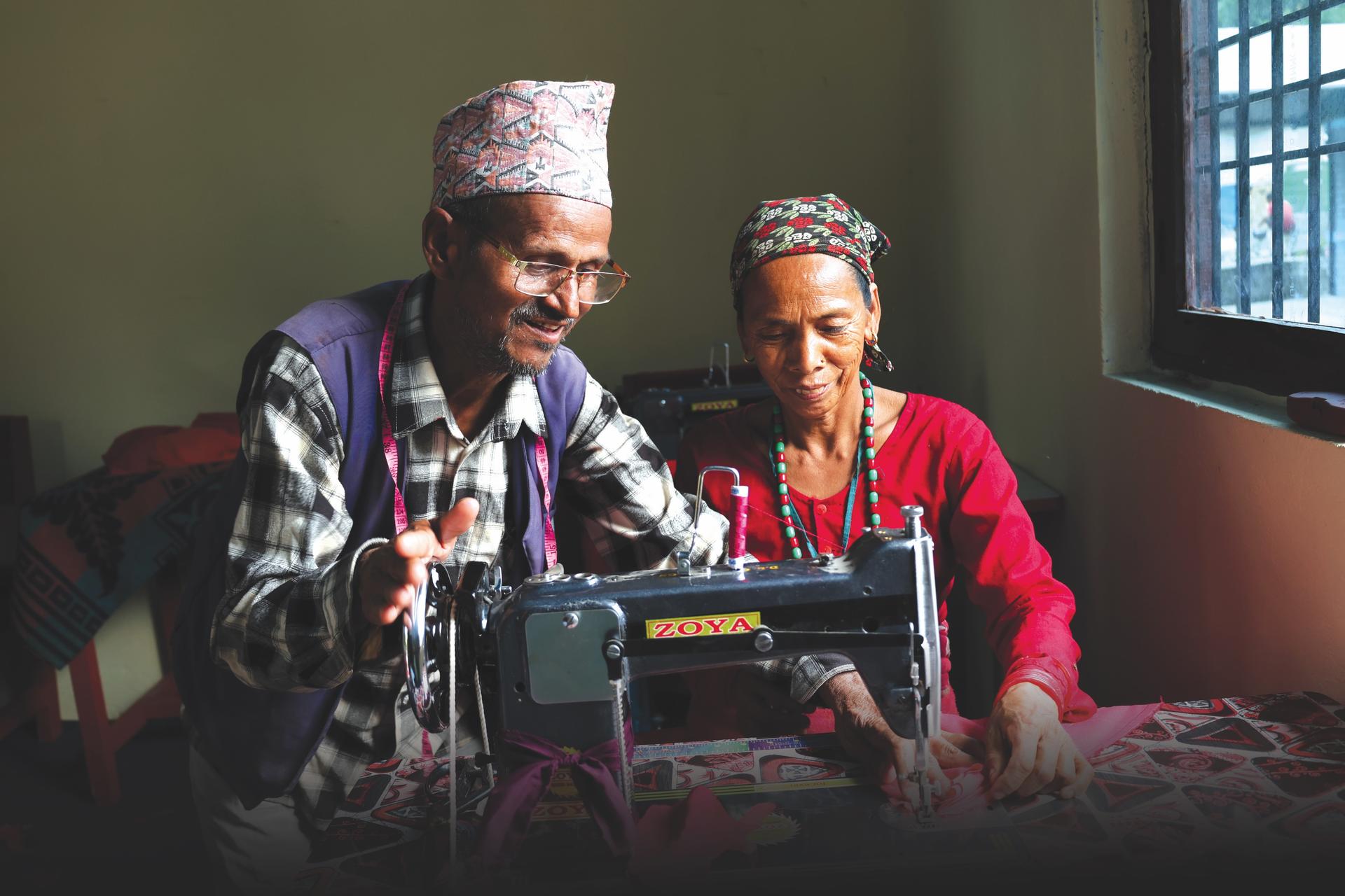 Two elderly people sewing on a vintage sewing machine beside a window.