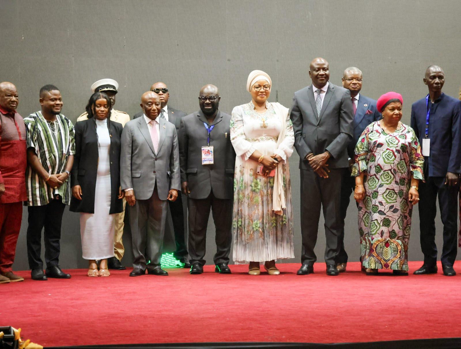Group of dignitaries in formal attire standing on a red carpet against a gray backdrop.