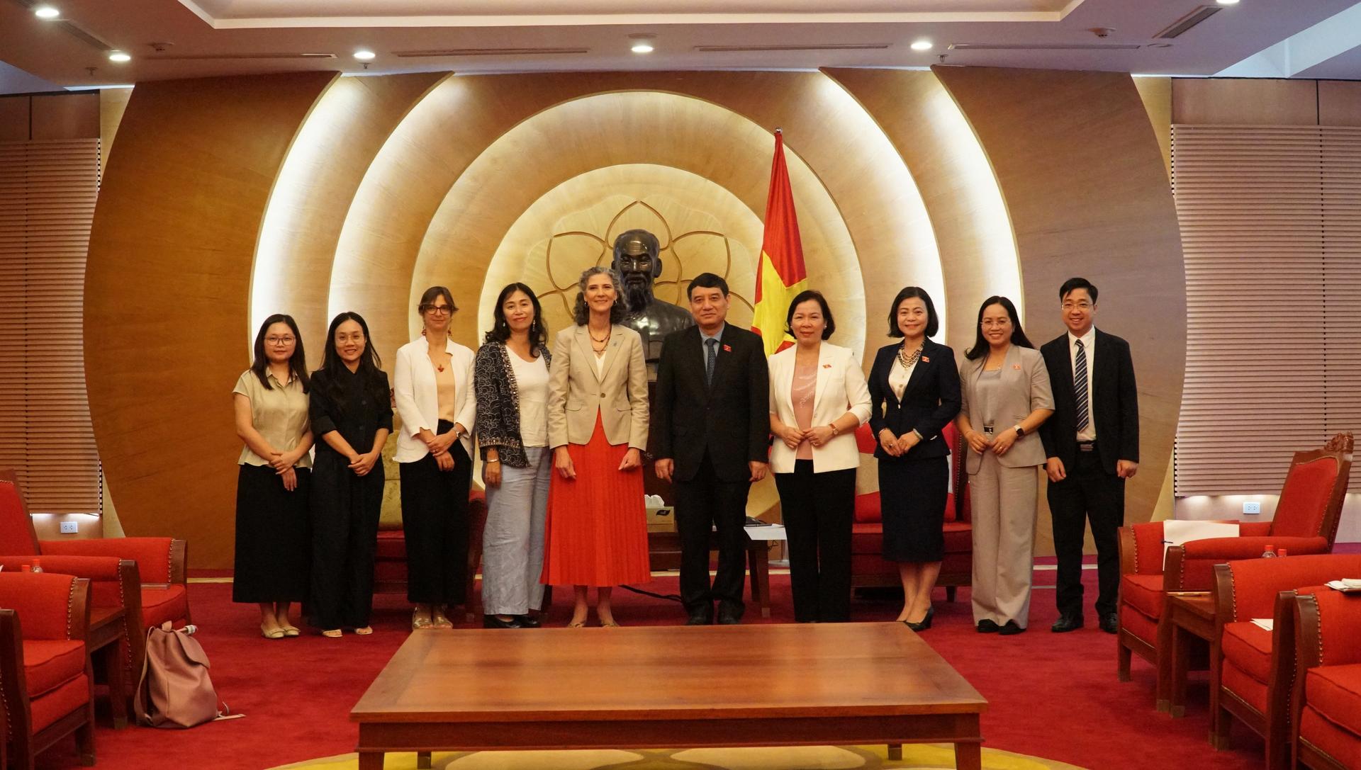 Group of people in formal attire posing on stage in a conference hall with a round emblem backdrop.