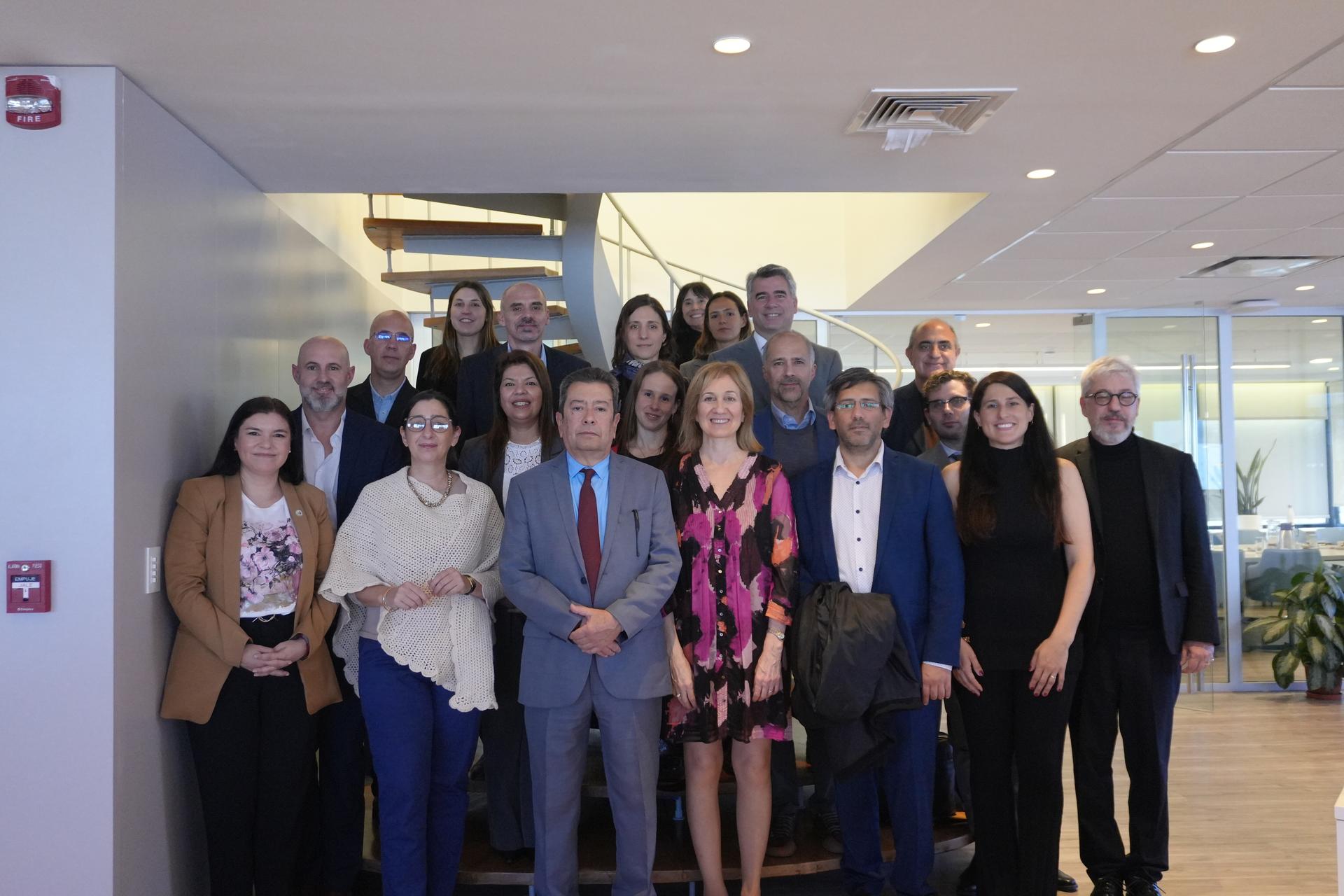 Diverse group of professionals smiling on a staircase in a bright office lobby.