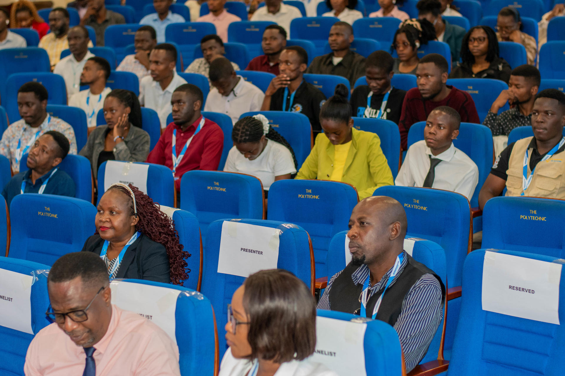 Diverse audience seated in bright blue stadium seats at an event.