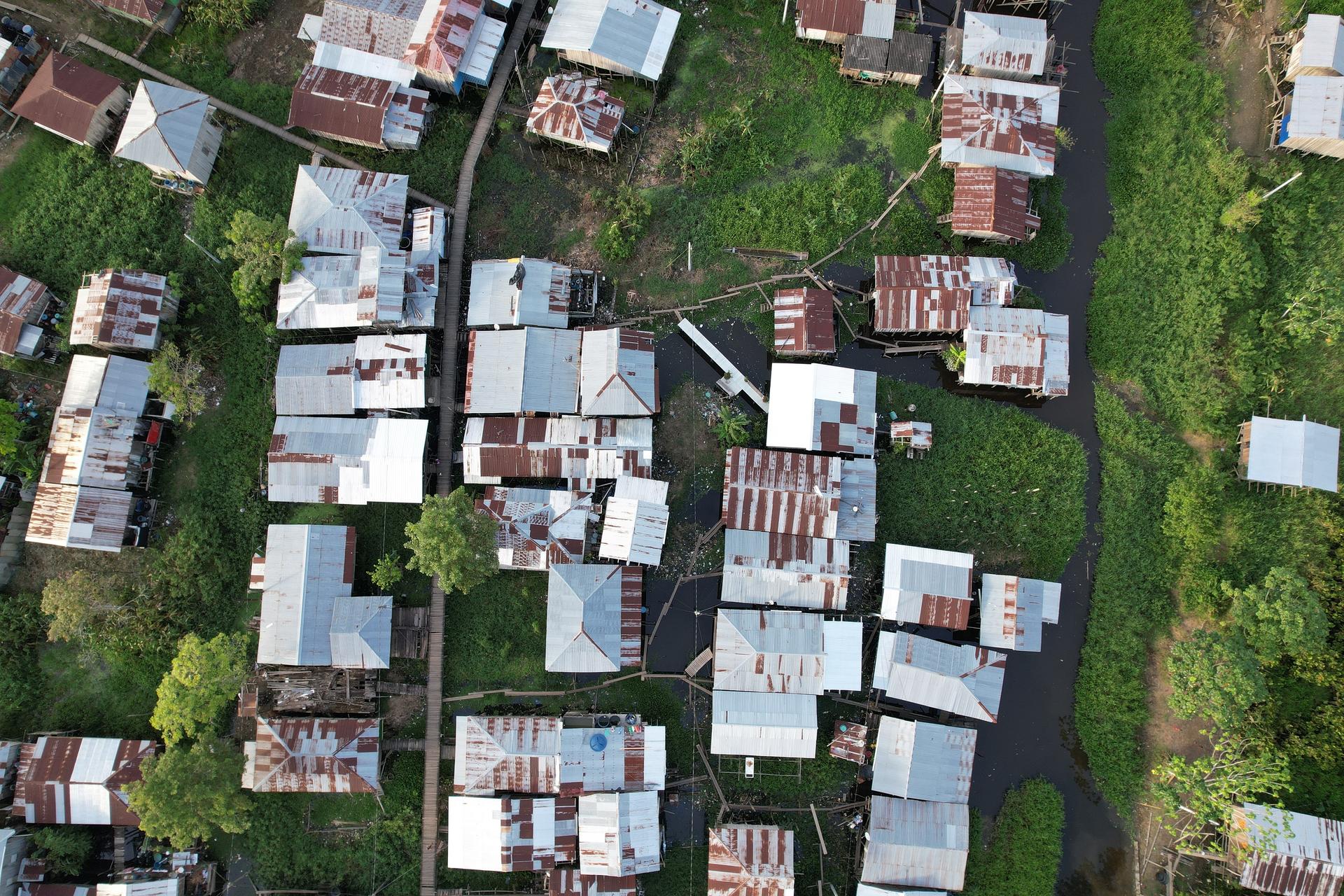 Aerial view of a densely packed residential area with varied roofs and surrounding greenery.