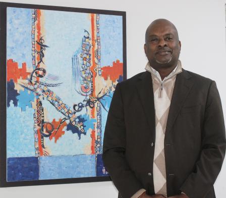 Un homme debout habillé en noir à côté d'un tableau dart