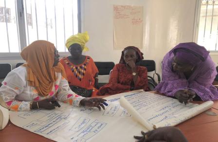 4 femmes assises devant de grandes feuilles de papier