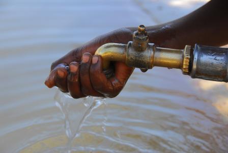 Hand collecting water coming out from a pipe