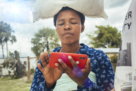 Woman with rice bag on her head using a mobile phone