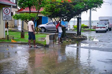 Men try to unclog a drain in Buccoo after flash flooding occurred during the passage of Hurricane Beryl on July 1