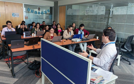 Un grupo de personas sentadas en una mesa usando una computadora portátil
