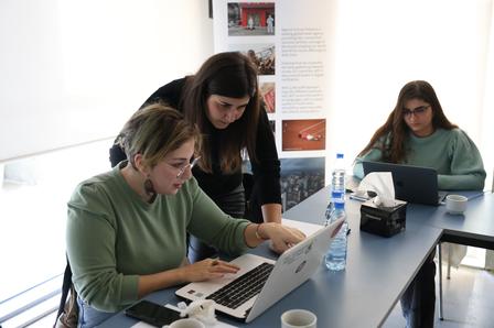 a woman sitting at a table using a laptop computer
