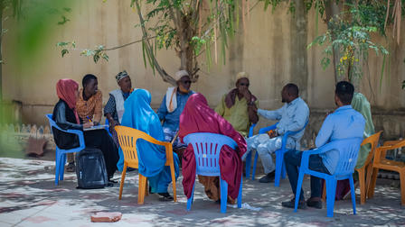 a group of people standing in front of a blue bench