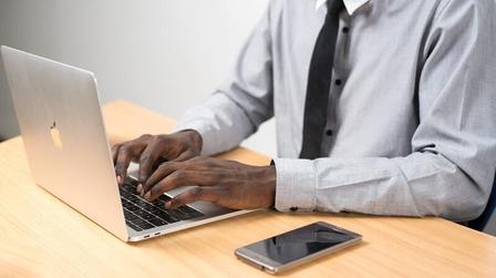 a man using a laptop computer sitting on top of a table