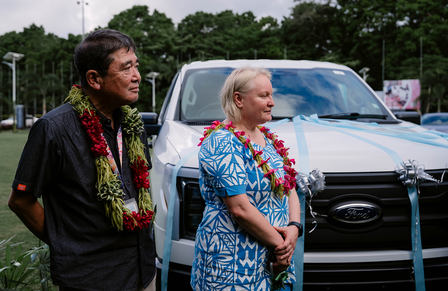 a man and a woman standing in front of a car
