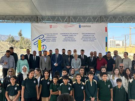 Kameraya poz veren bir kalabalığın önünde duran bir grup insan