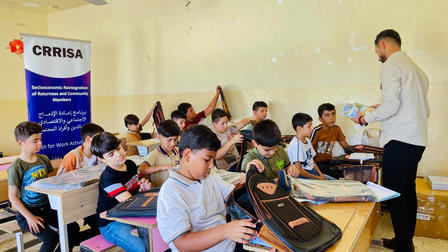 a group of people sitting at a table looking at a laptop