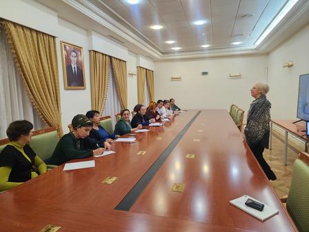 Eleven people seated at a long table in a conference room, engaged in a discussion.