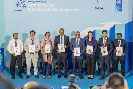 a group of people posing with the report at the launch of the maldives sustainability framework
