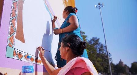 two women painting on a wall