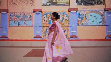a little girl standing in front of a wall painting