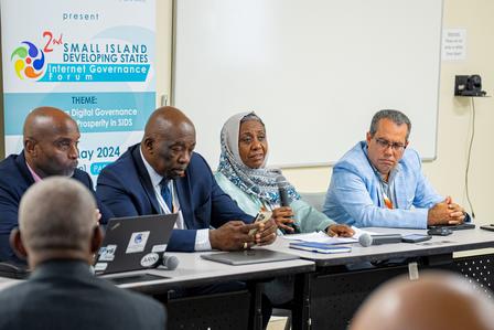 A panel of four individuals seated at a conference table, engaged in discussion.