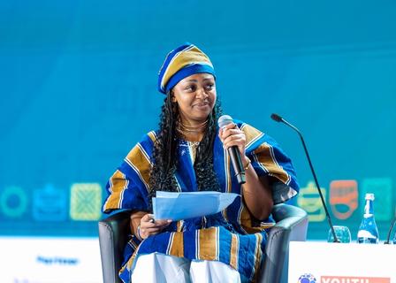 A woman speaks into a microphone at a conference.