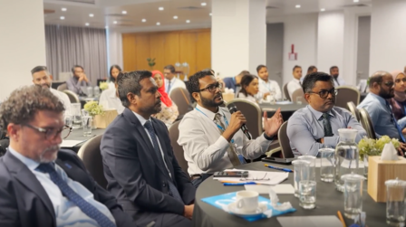 Professionals engaged in discussion at a conference with refreshments on the table.
