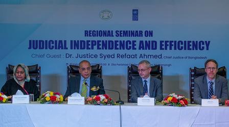 Panel of speakers seated at a conference table, discussing judicial independence and efficiency.