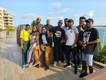 Group of ten people posing together outdoors, with a scenic view in the background.