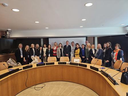 A diverse group of people poses together in a conference room with a round table.