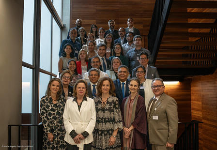 A diverse group of professionals poses together on a staircase in a modern building.