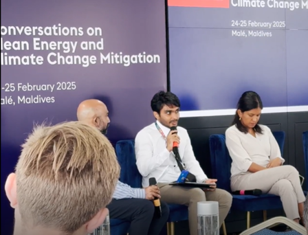 Three people seated at a panel discussion, with a backdrop on climate change and energy.
