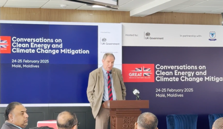 A speaker stands at a podium during a conference on clean energy and climate change.
