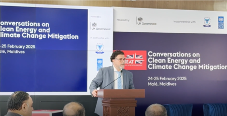 A man in a suit speaks at a podium during a conference on clean energy and climate change.