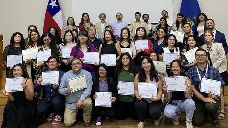 Group photo of diverse individuals holding certificates, celebrating an achievement.
