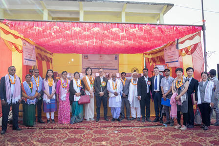 Group of people in formal attire posing at an outdoor event under a colorful canopy.