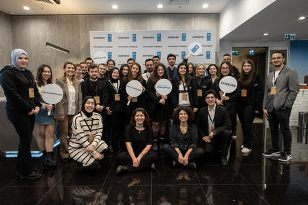 Group photo of diverse individuals posing together in a modern indoor setting.