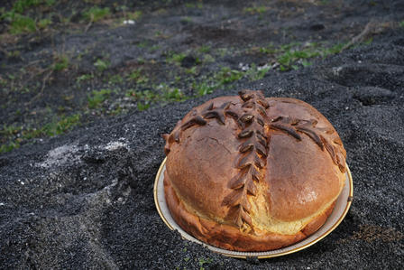A round, decorative bread sitting on a rocky surface, featuring a braided top design.