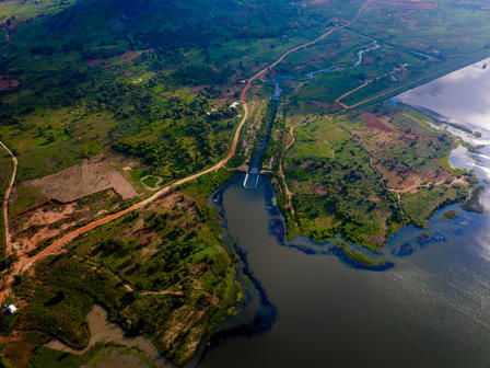 Aerial view of lush green landscape with winding roads and rivers meeting a lake.
