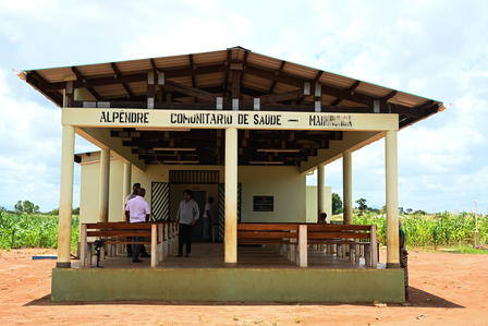 Health clinic building with a spacious porch, surrounded by green fields under a blue sky.