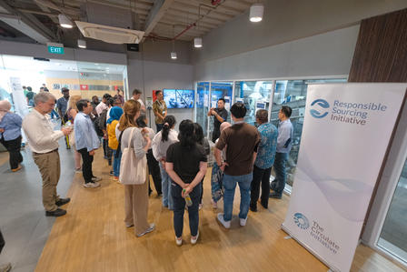 A diverse group of people gathered in a modern exhibition space, engaging with displays.
