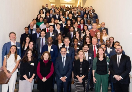 A large group of diverse professionals posing together on a staircase, smiling.