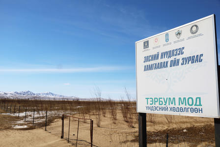 A sign in a barren landscape, with mountains in the background and a clear blue sky.