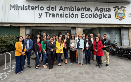 Group photo of diverse individuals in front of the Ministerio del Ambiente building.