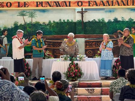 A group of people stand at a table adorned with flowers, celebrating in a colorful venue.
