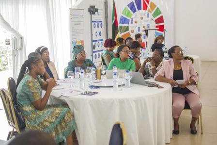 A group of women seated at a round table, engaged in discussion during a meeting.