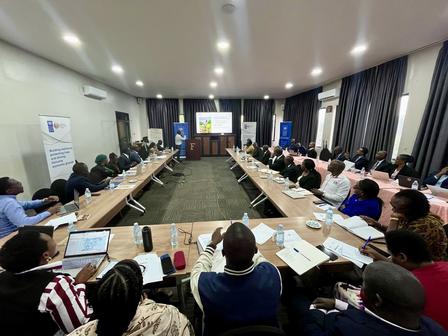 A conference room filled with attendees seated at long tables, engaged in a discussion.